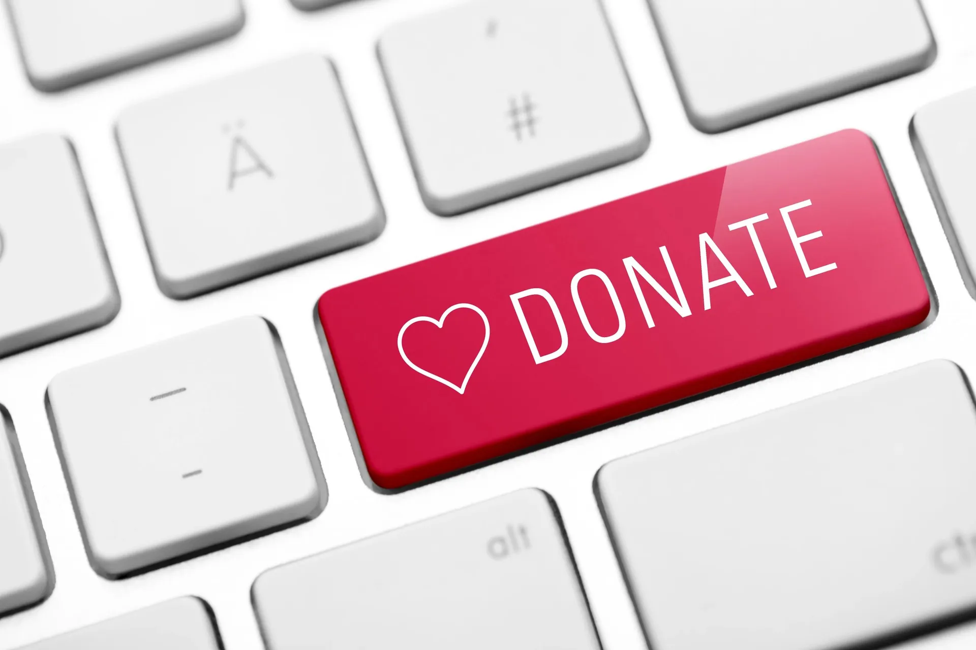 Red donate key with a heart symbol on a white keyboard