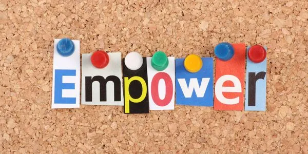 The word Empower spelled out with colorful letters pinned on a corkboard